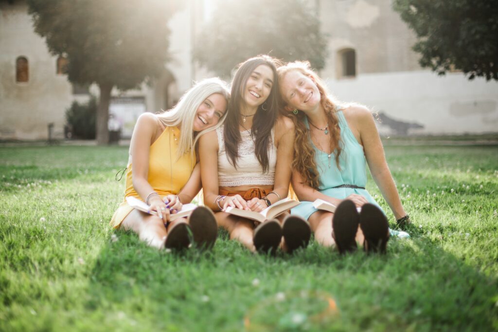 Happy Girls Smiling Sitting On Grass. to live life to the fullest