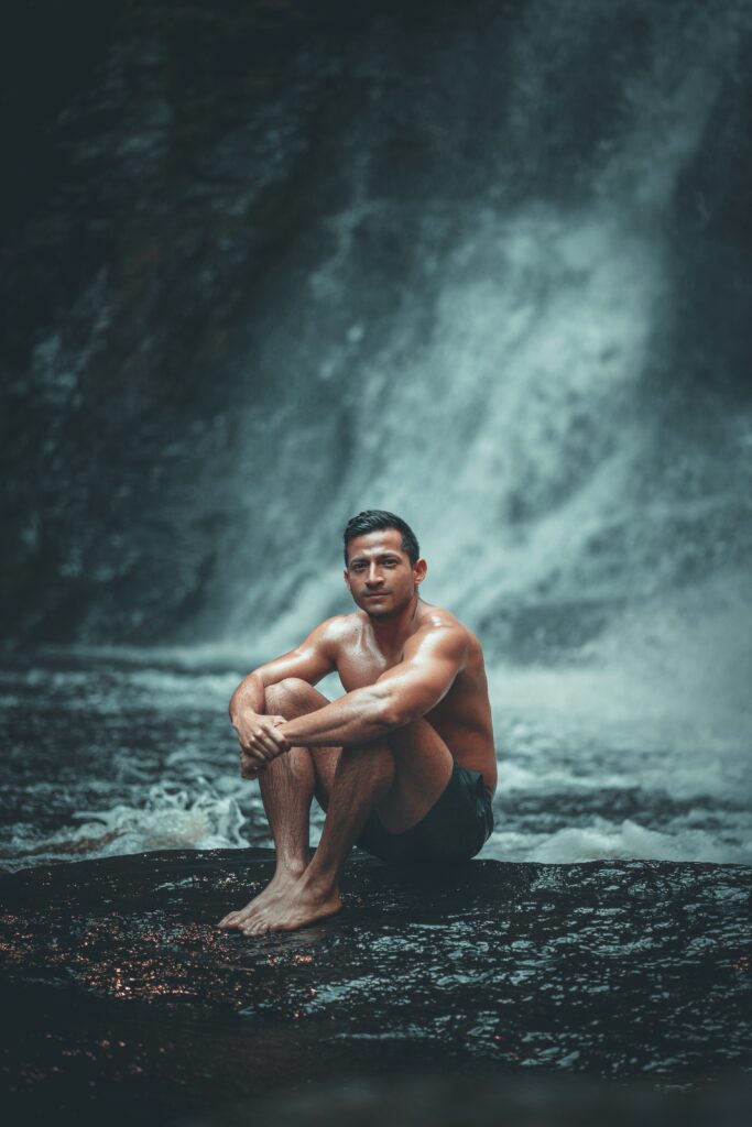 Young Healthy Man Sitting By Waterfall.to live life to the fullest