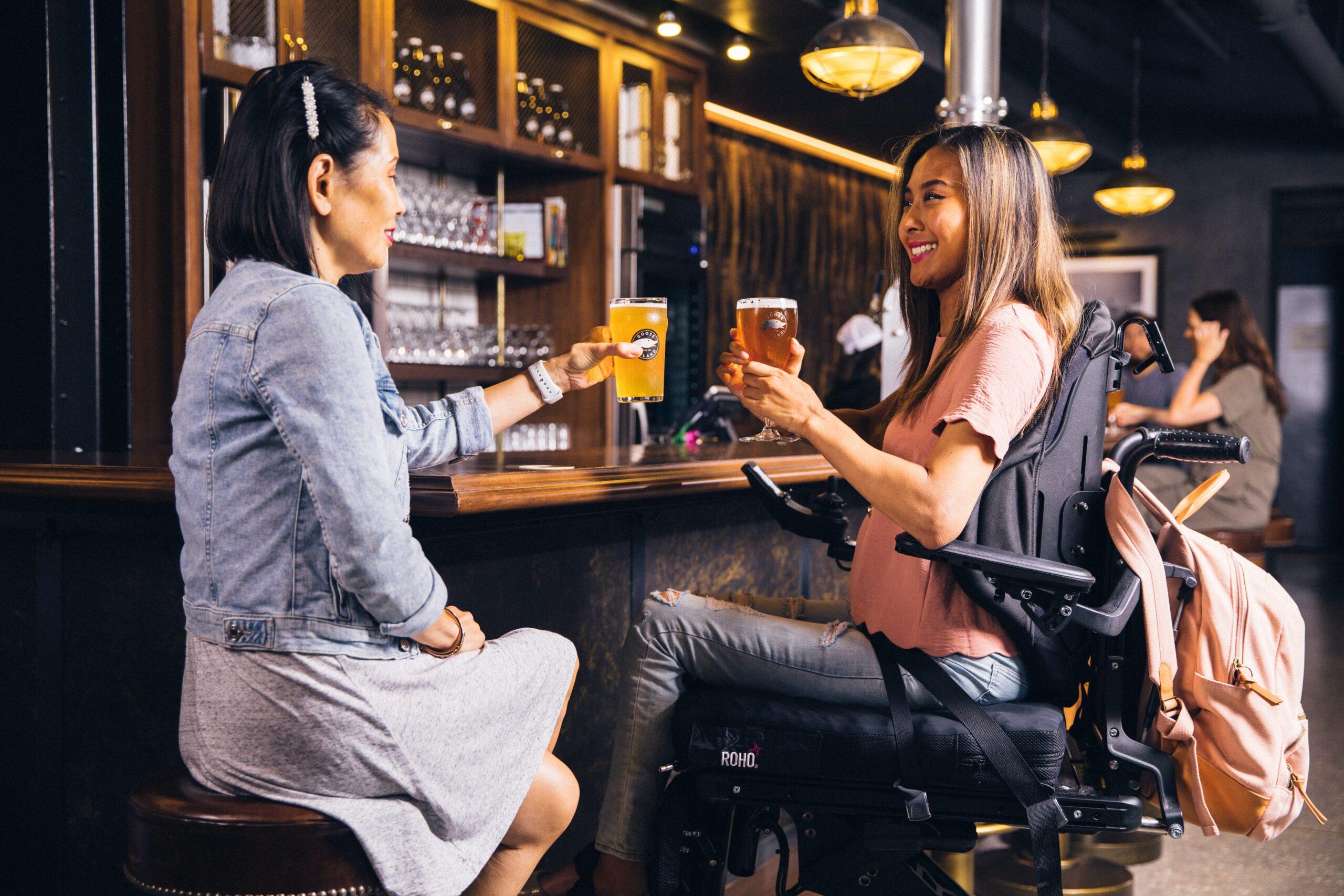 Disabled Person In Wheelchair Having Ad Drink In Pub.