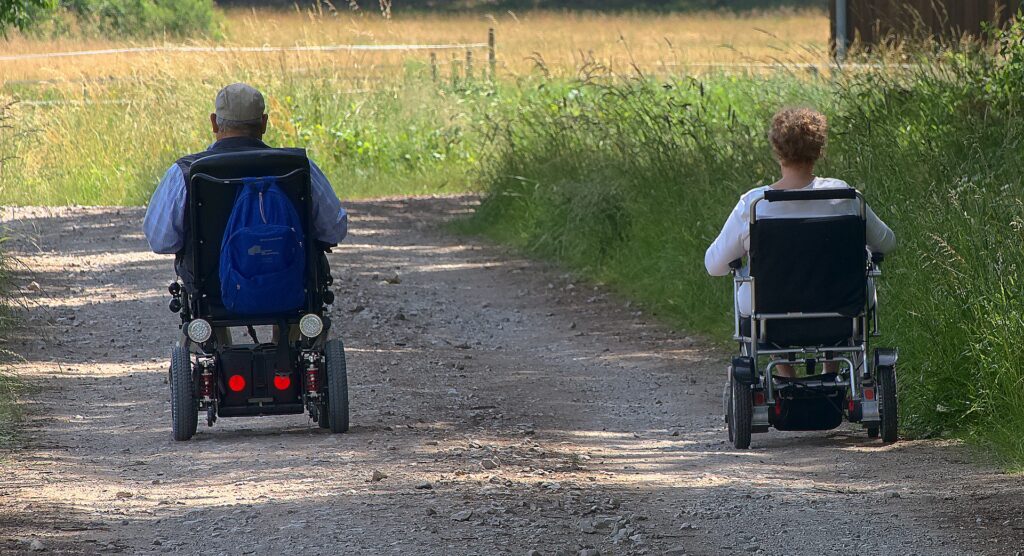 2 People In Electric Wheelchairs In The Countryside. Unlocking Independence: How Wheelchairs Empower Individuals with Mobility Challenges