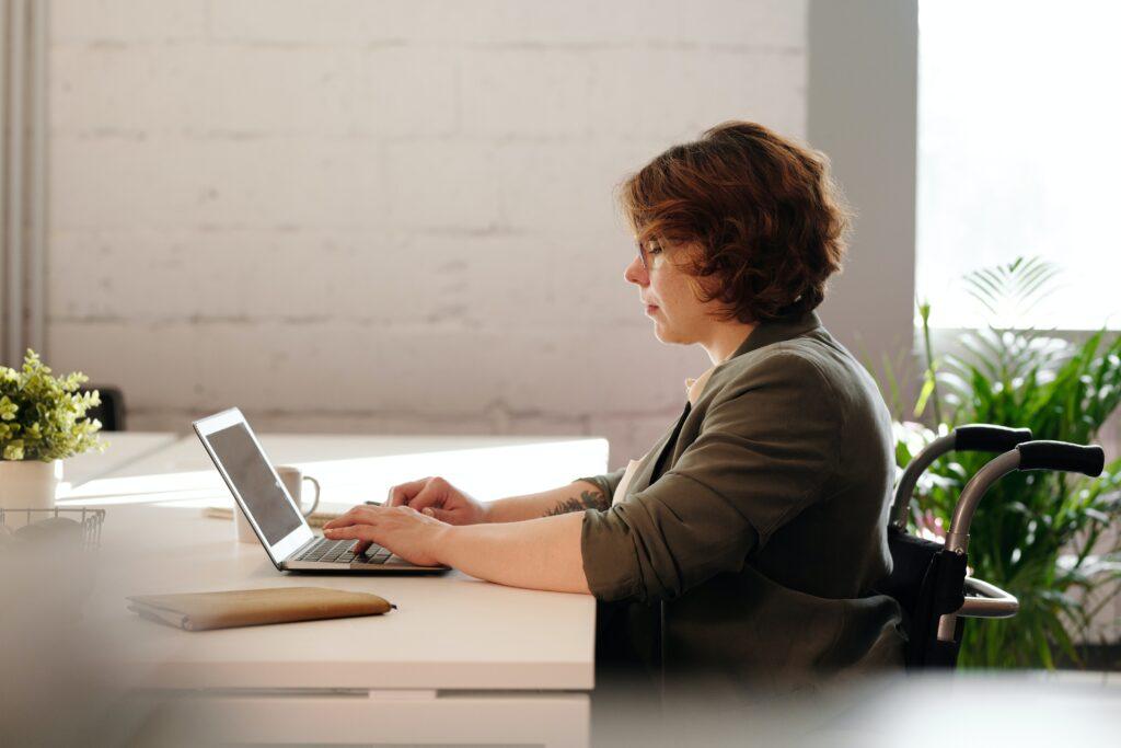 Disabled Lady In Wheelchair Using Lap top.