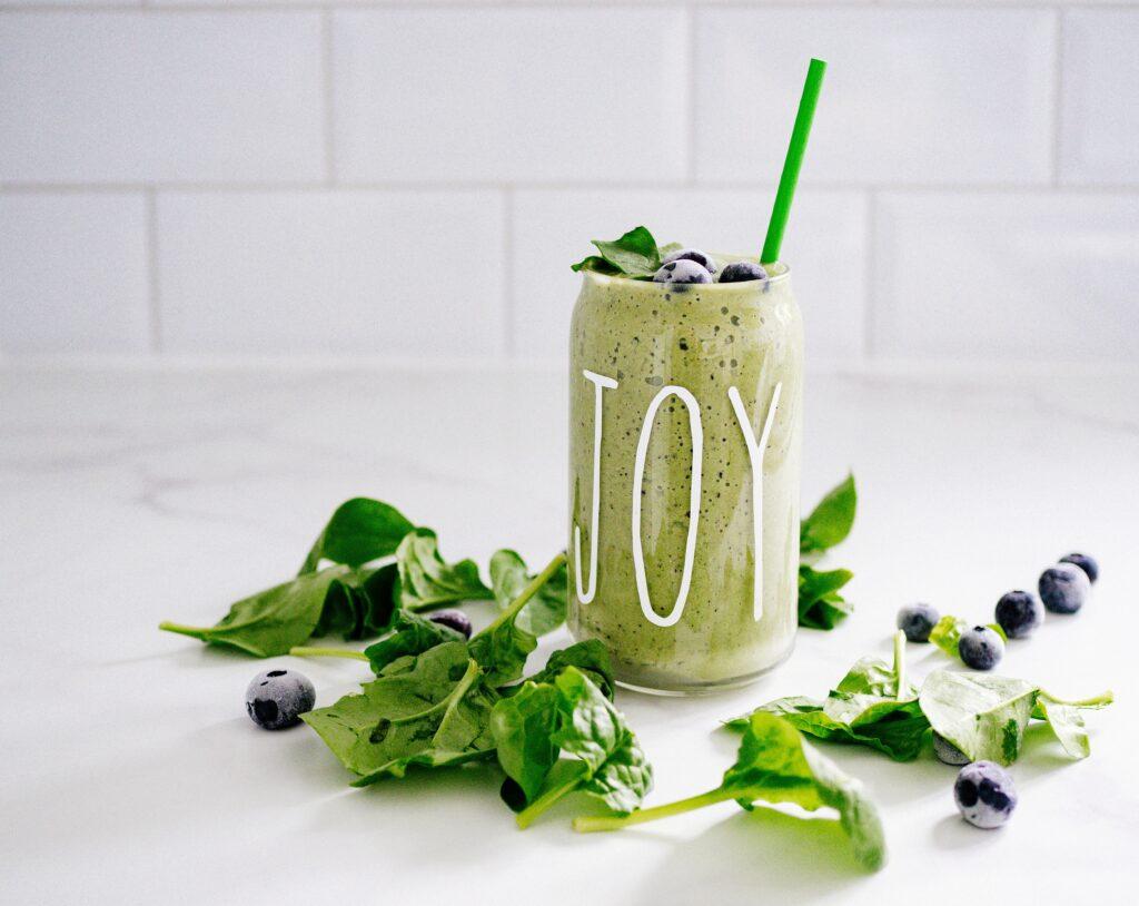 Green Smoothie In Tall Glass With Strae Joy Written On Gleass